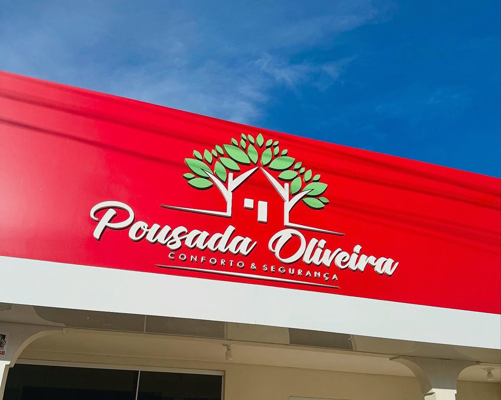 Fachada da Pousada Oliveira: letreiro vermelho com o logotipo da casa sob o céu de Remanso.