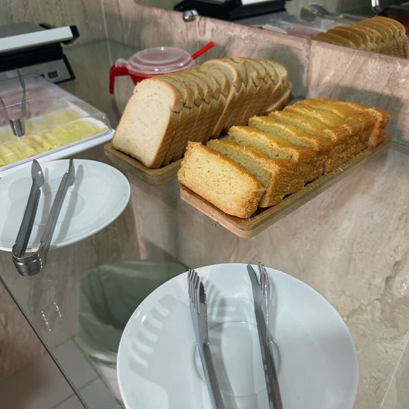 Pães e bolo de fubá fatiados no balcão do café.